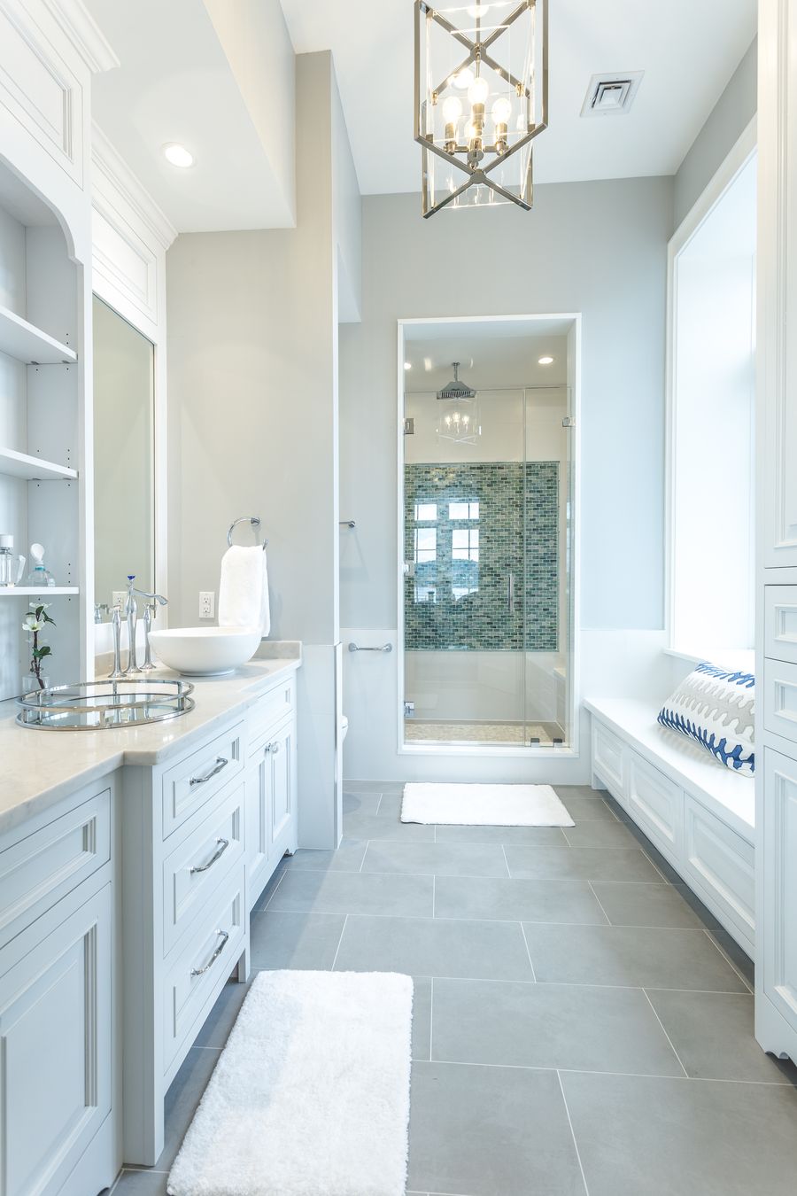 Full bathroom with cabinetry on both sides and a built-in window bench by Division Seven Millwork