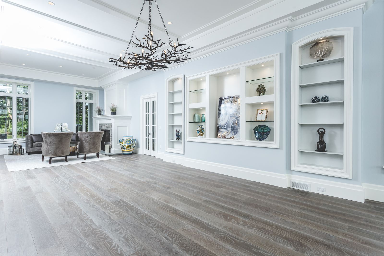 Arched built-in display wall with lit shelving niches by Division Seven Millwork