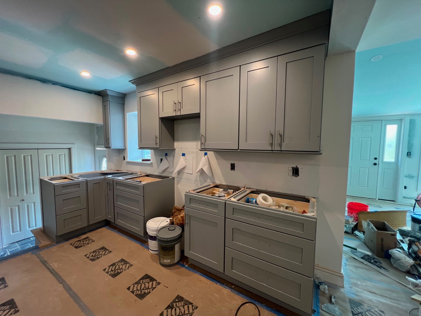 Gray shaker kitchen cabinetry fitted around a corner and arched window in an older Hudson Valley home by Division Seven Millwork