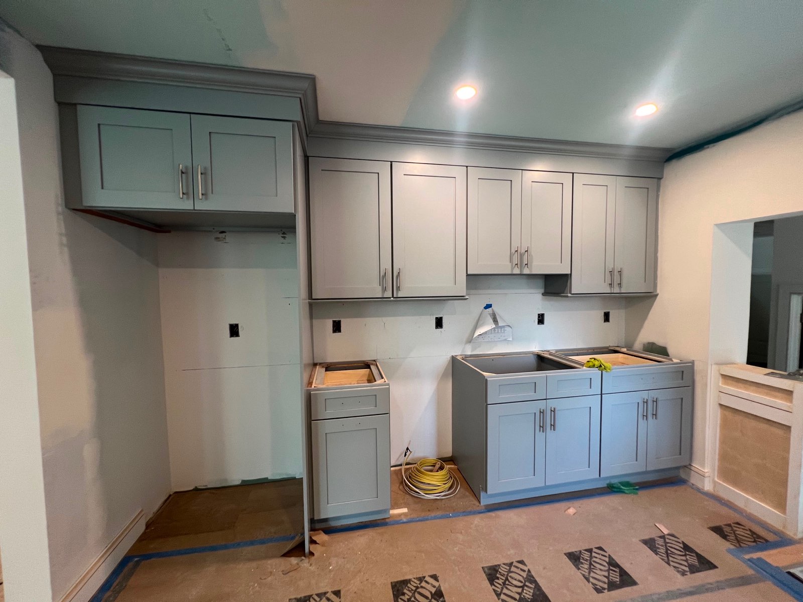 Gray shaker upper and base cabinets installed with crown molding before countertops by Division Seven Millwork