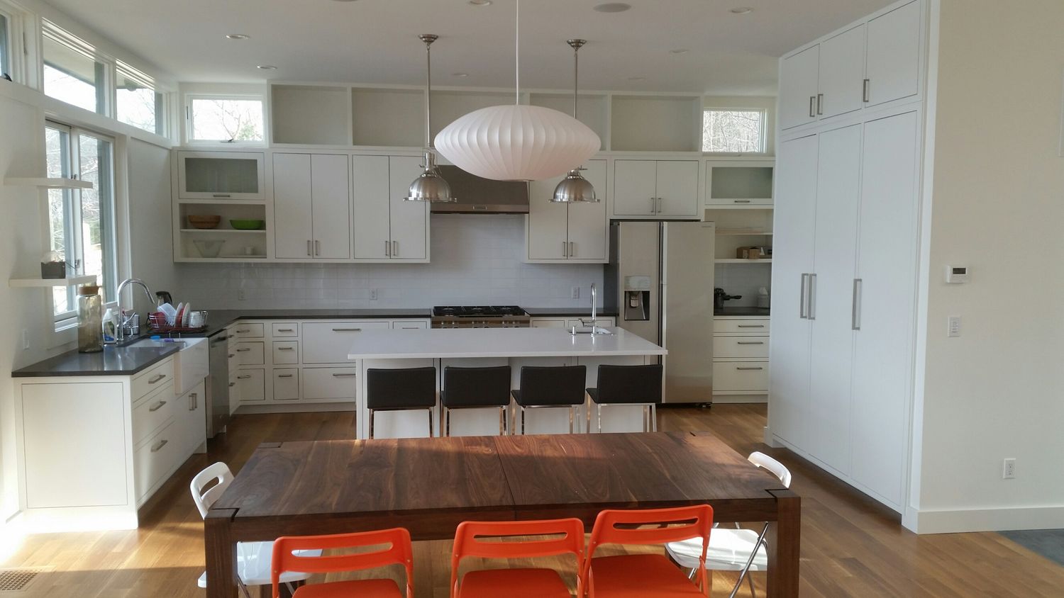 Modern white kitchen remodel with island and dining area by Division Seven Millwork