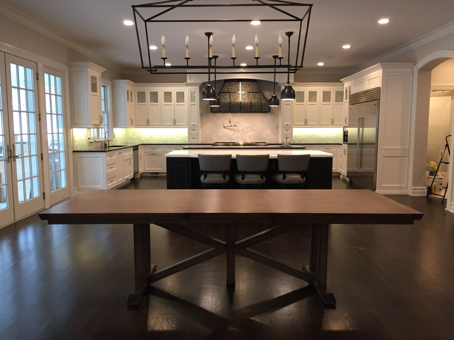 Large white kitchen remodel with oversized island and linear lantern by Division Seven Millwork